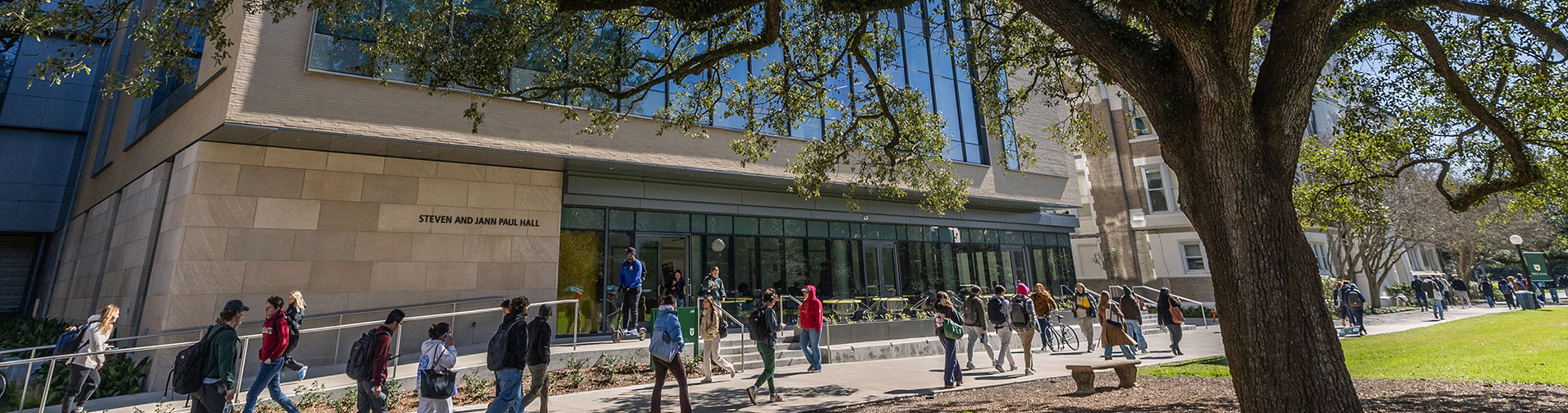 Students walk by the front of Paul Hall on a sunny day. 
