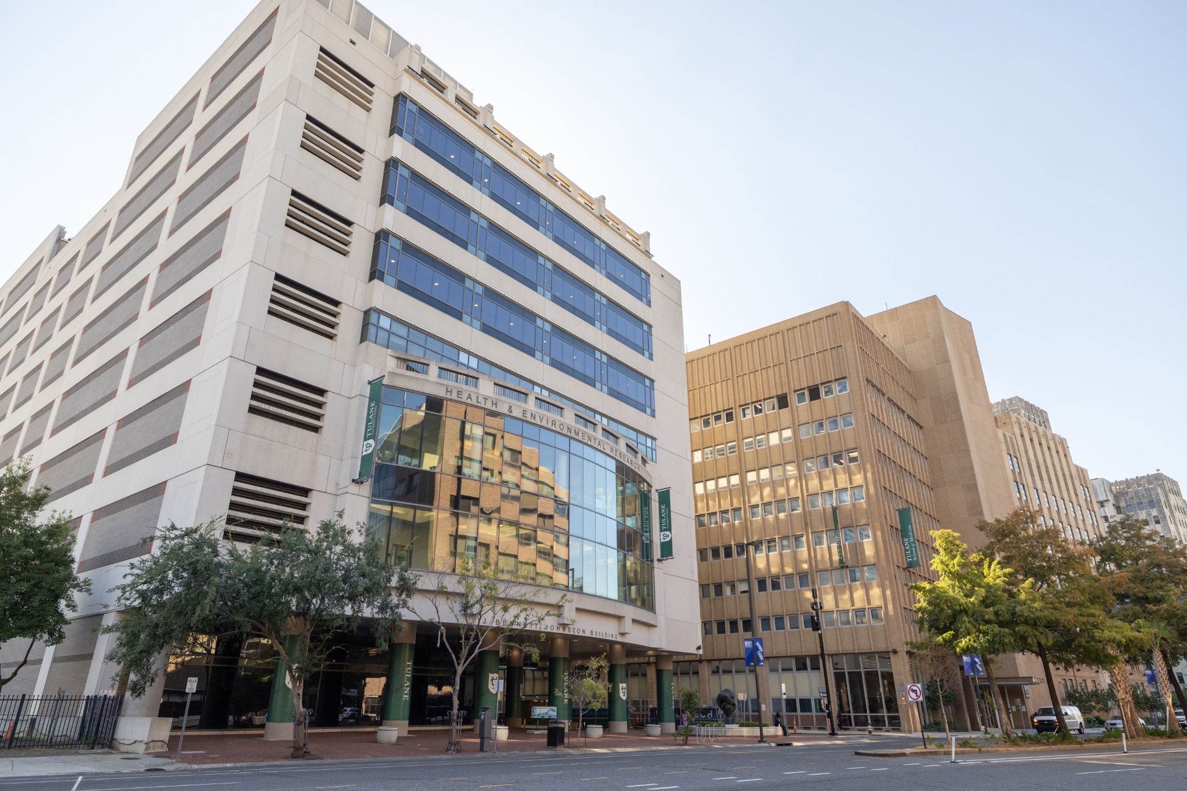 Large, light-colored office building with a curved glass front, next to a brown building.